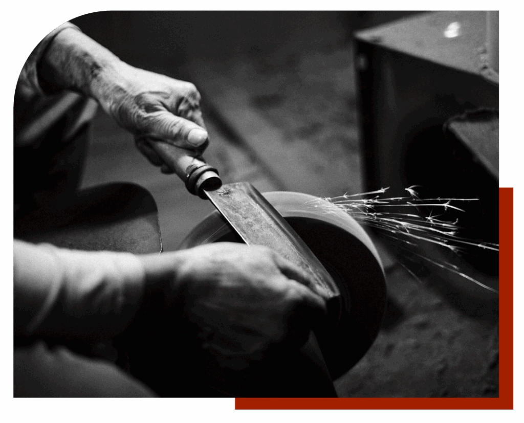 Maestro afilador afilando un cuchillo en una rueda de piedra.